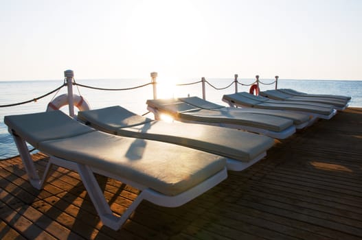 Ten chaise-longues on a wooden pier and sunrise