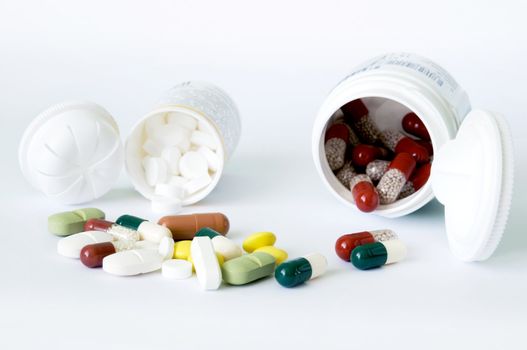 Different forms and colours tablets and capsules and two white bottles