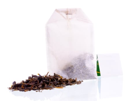 Heap of tea loose and teabag with white label. Focus on teabag