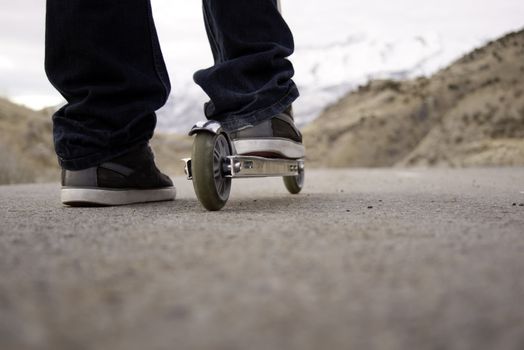 child riding scooter on paved pathway with mountains in background