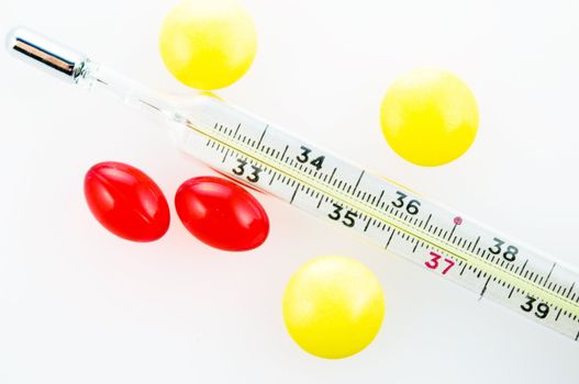 Thermometer with 37,5 level and three yellow tablets and two red capsules
