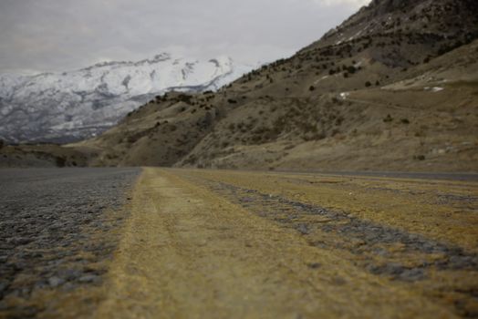 view of mountains and road from very low viewpoint bright yellow striping shallow depth of field