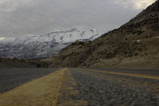 view of mountains and road from very low viewpoint bright yellow lines in roadway