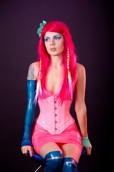 Young woman dressed in bright latex clothes, studio shot 