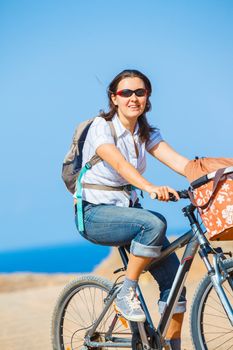 Woman on bike outdoors smiling. Vertical view