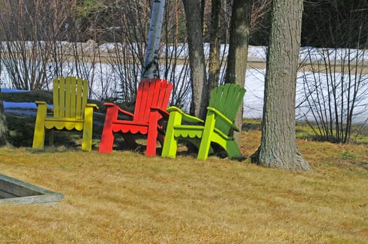 Adirondack chairs in a yard during an early srping