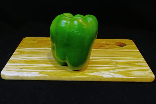 A sweet green pepper on a wooden tray