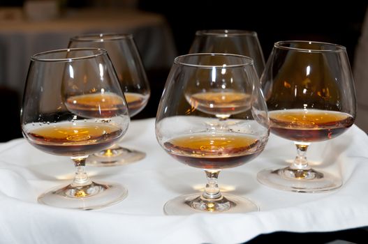 Classical glasses with cognac on white tray