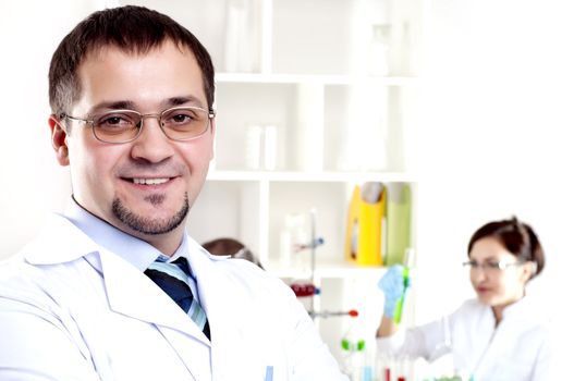 Three doctors are smiling at the camera in a doctors' office. Horizontally framed shot.