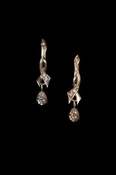 Shining elegant modern earrings with zircons isolated on black