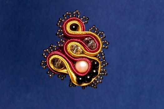 Soutache modern brooch with beads on violet background