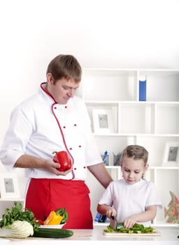 portrait of father and daughter cooking salad together in the kitchen