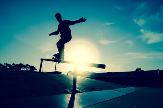 Skateboarder silhouette on a grind at the local skatepark.