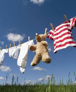 Baby Clothing and a teddybear on a clothesline towards blue sky