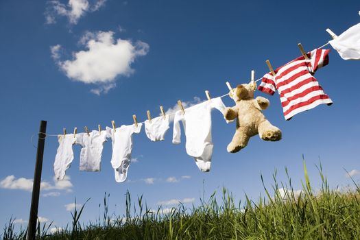 Baby Clothing and a teddybear on a clothesline towards blue sky