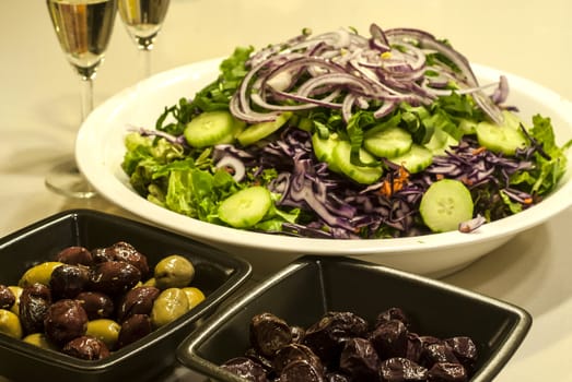 Mixed salad dish, olives, white wine glasses