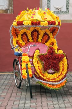 One of the many Tricycle Rickshaws for Tourist Rides Decorated with Bright Colorful Silk Flowers in Melaka Malaysia