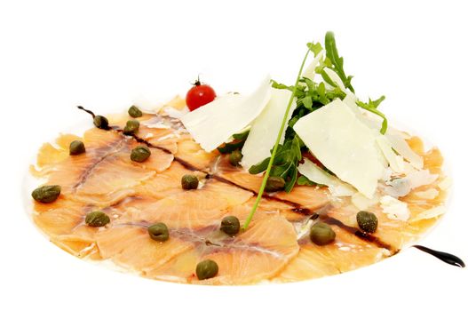 Fish carpaccio with green on a white plate