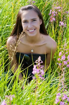 Outdoor shot of beautiful brunette woman sitting in grass