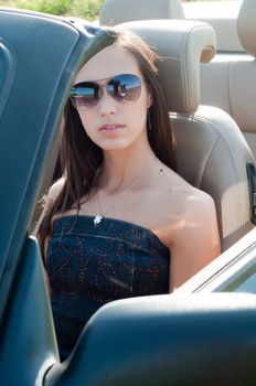 Brunette woman in sunglases sitting in cabrio