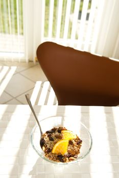 Healthy bowl of muesli with orange slices in the morning sun