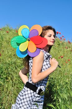 girl with windmill walking by the poppy field 