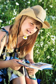 teen girl reading a book on the daisy meadow