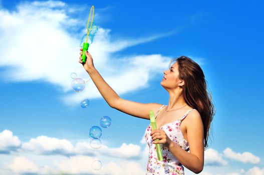 Beautiful young teen girl blowing soap bubbles 