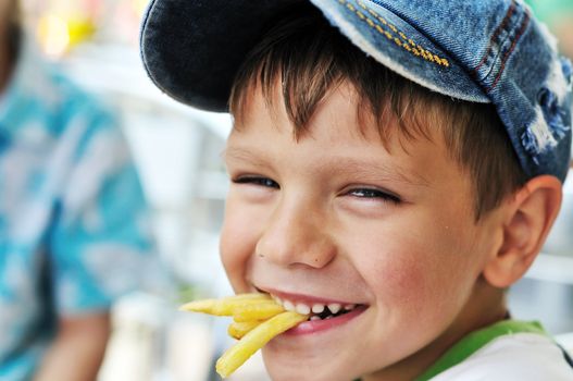 little boy eating french fries in cafe 