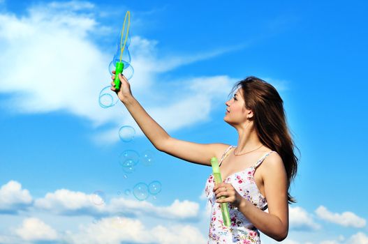 Beautiful young teen girl blowing soap bubbles