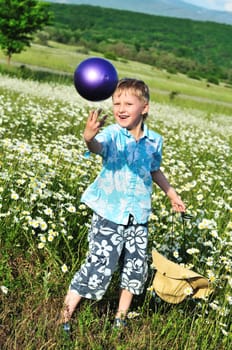 funny boy playing ball at the daisy field