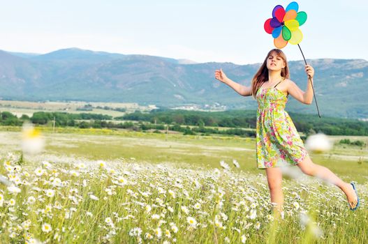 girl with windmill walking by the daisy field 