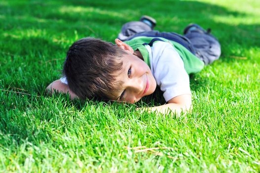 happy little boy laying on the sunny meadow 