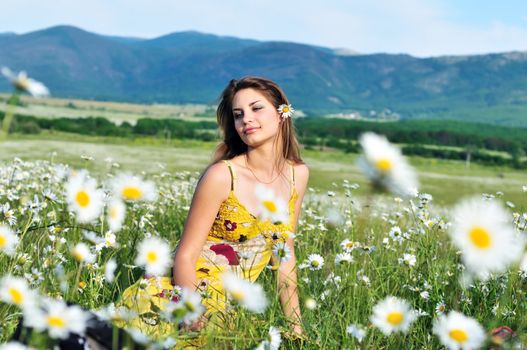 girl relaxing in the daisy field with flower in her hair