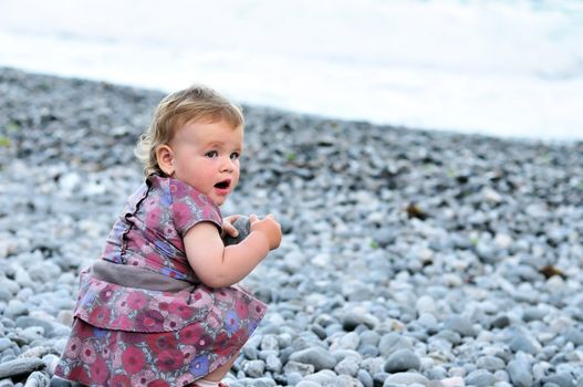baby girl playing with pebble near the sea