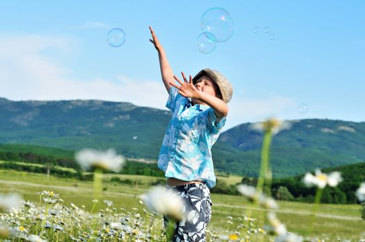 jumping little boy wants to catch soap bubbles 