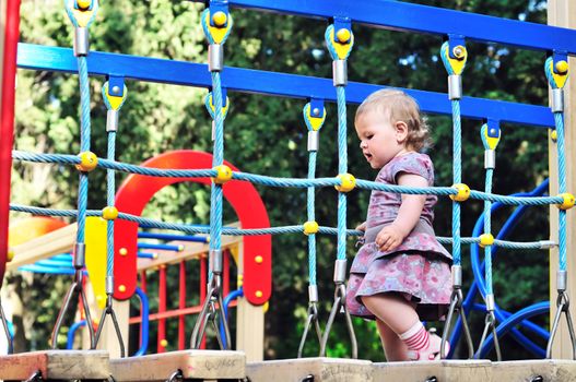 Little baby girl walking on playground in the park 