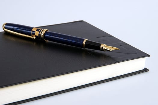 A closed personal organizer with a pen on top