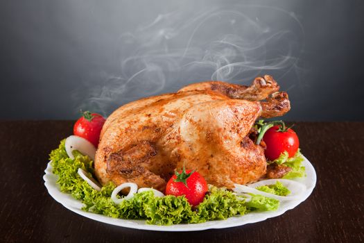 Delicious roast chicken with red tomatoes and green salad, studio shot 