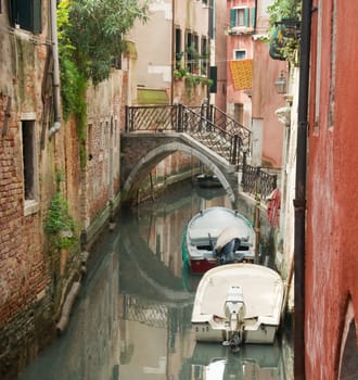 Canal, bridge, boats and reflections in Venice