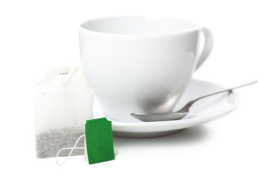 White cup and white saucer with teabag over white background