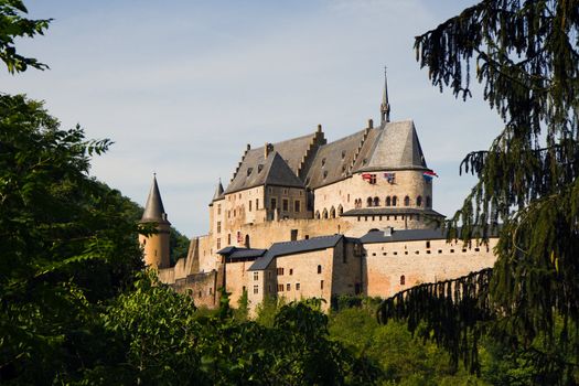 Vianden, Medieval castle on the mountain in Luxembourg or Letzebuerg, view through the trees - horizontal image