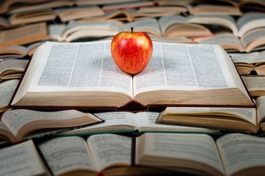 Red and delicious apple on big heap of books