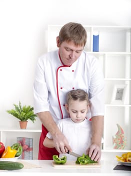 portrait of father and daughter cooking salad together in the kitchen