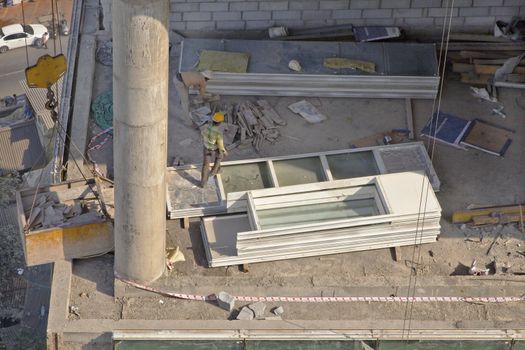 Mumbai, India, man at work on a construction site walking over new windows perhaps causing damage if need to be replaced