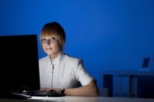 beautiful young woman doctor working at night in the office, smiling