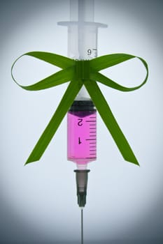 syringe with a pink liquid with a ribbon of grass with a vignette