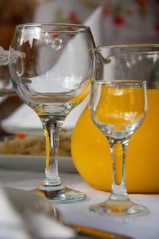 large and small glasses are on the table next to the orange juice