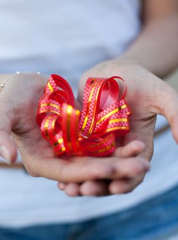 young woman holds a gift red bow in hands