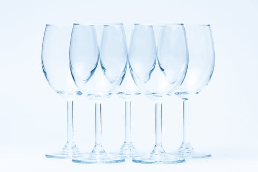 Empty wine glasses stand symmetrically on a white background